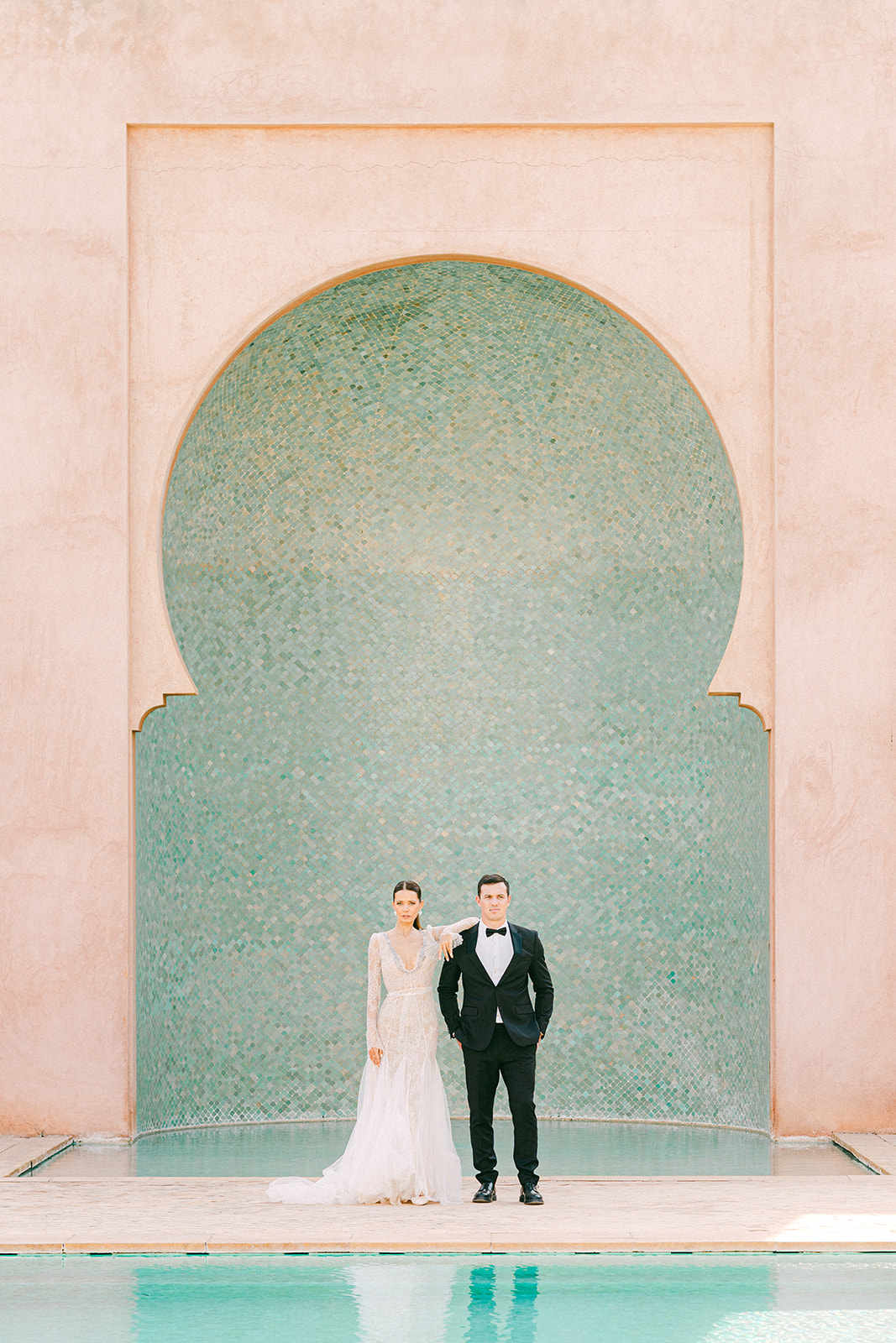 Stylish bride and groom posing in front of the pool at a luxury Marrakech wedding venue