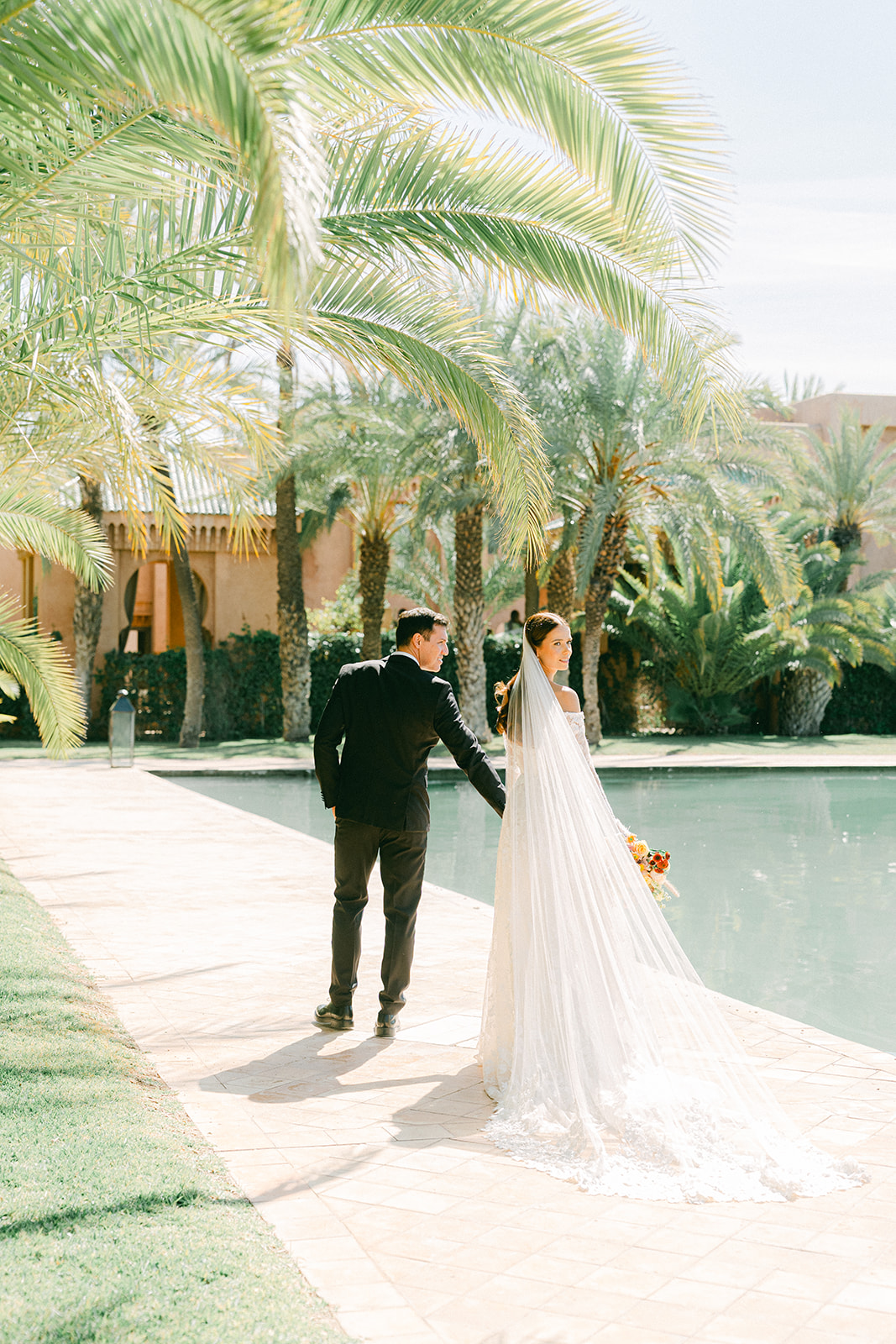 Candid moment during styled Morocco wedding shoot with the couple walking through Amanjena