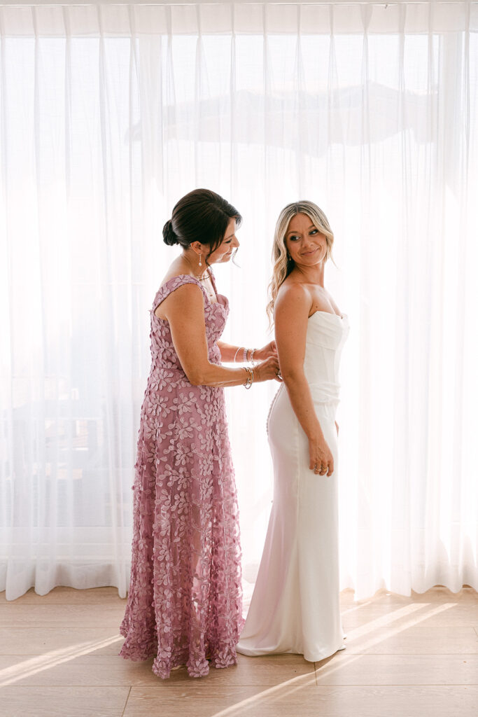 Getting ready photos of the bridesmaid helping the bride