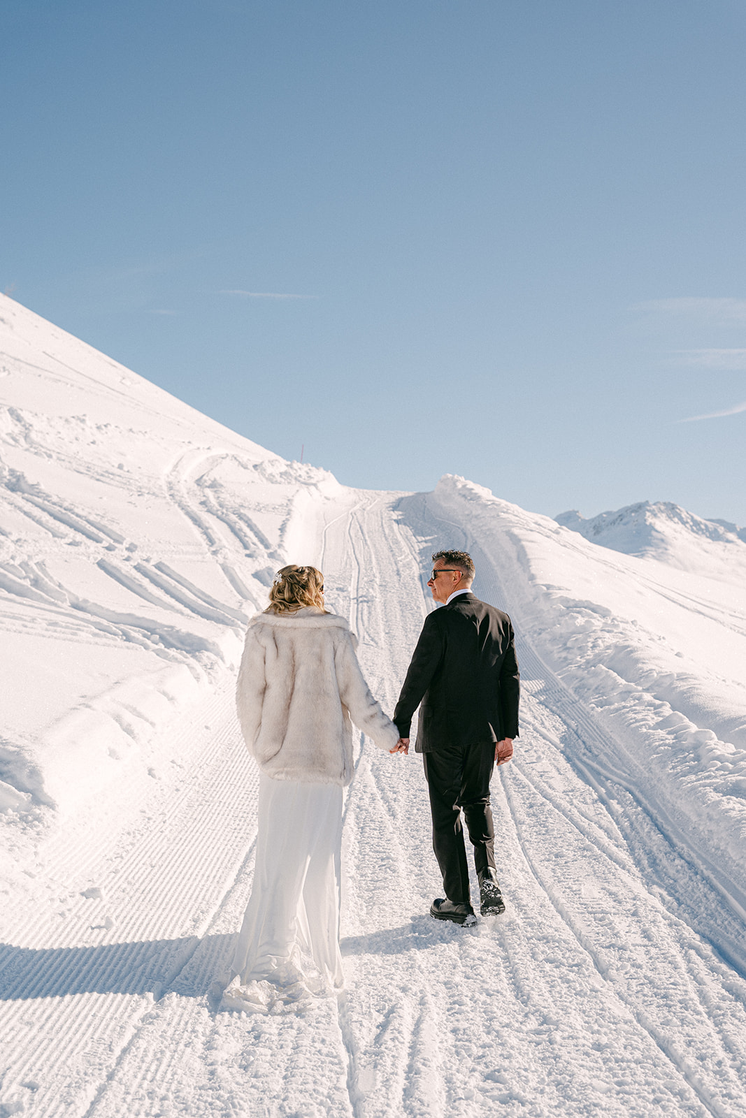 Bride and groom walking hand in hand during a winter mountain wedding