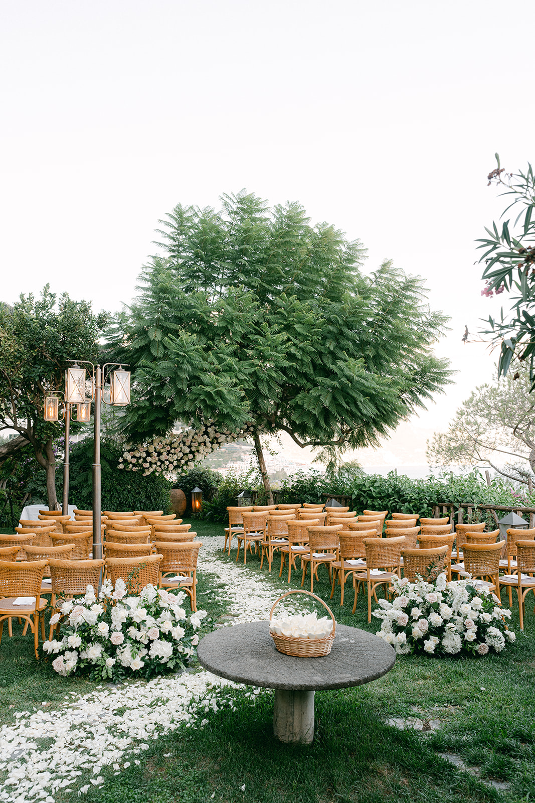 Elegant outdoor ceremony setup with white florals and sea backdrop.