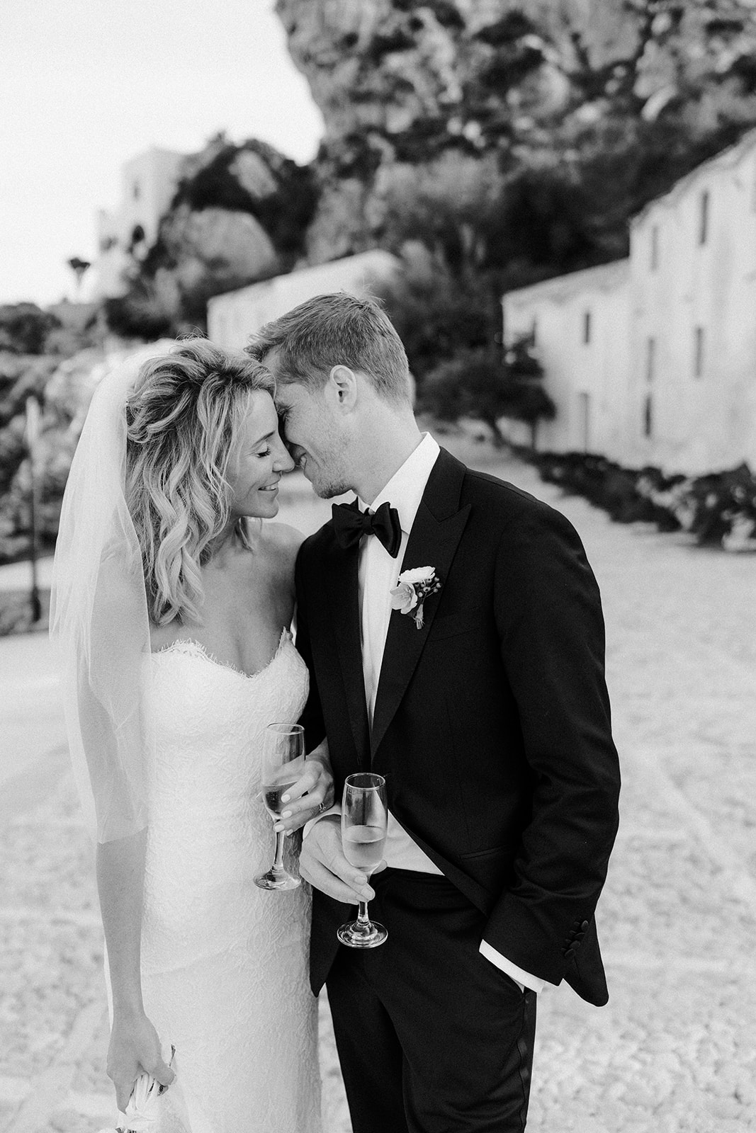 Bride and groom walking along the cliffs at Tonnara di Scopello during their wedding in Sicily with waves crashing below.