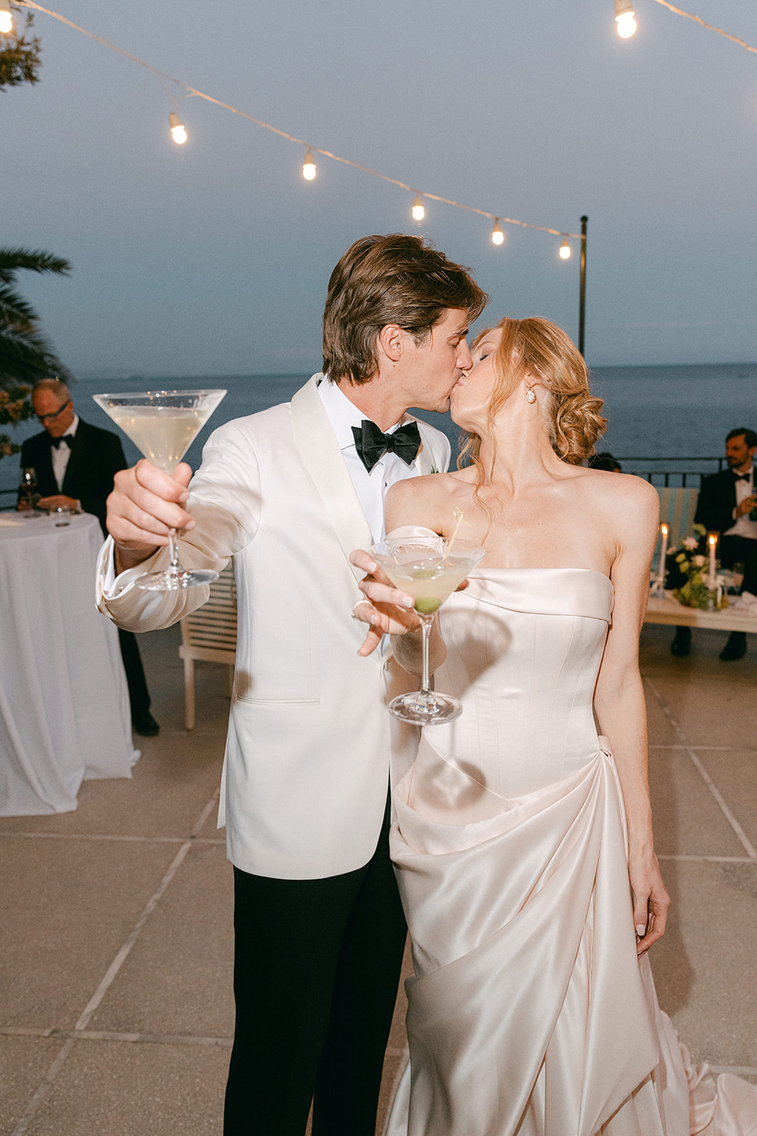 Couple pouring martinis into a modern martini tower at their wedding.