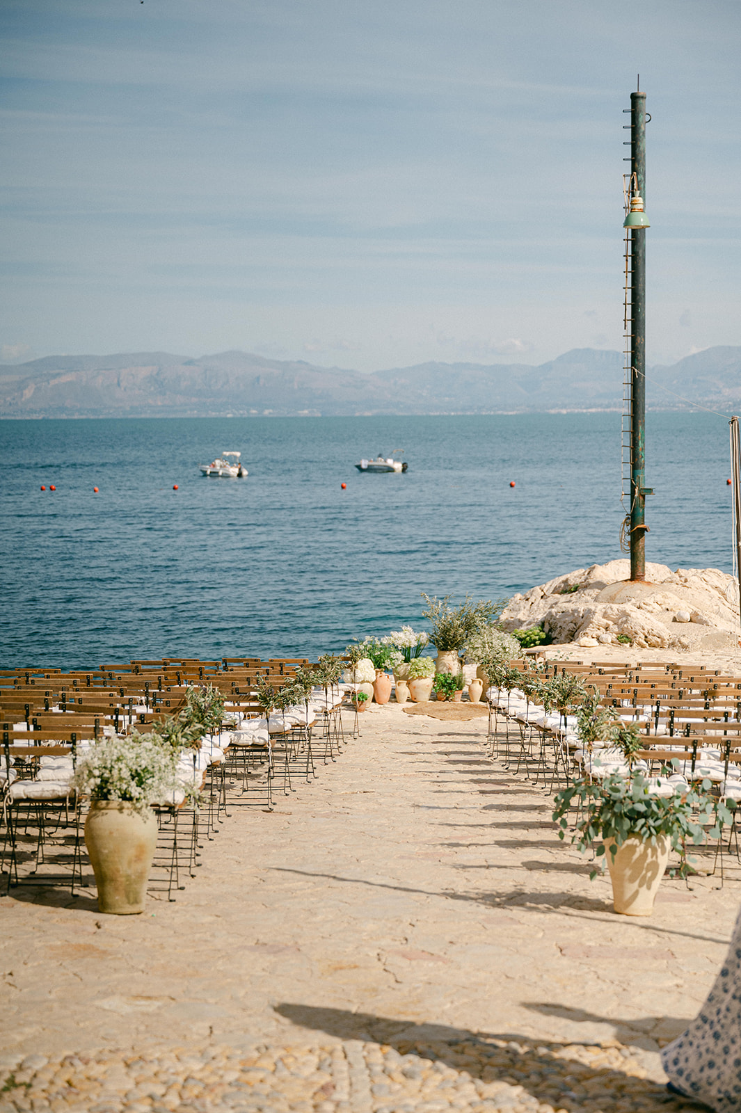 Sea-view ceremony setup at Tonnara di Scopello with simple white chairs and turquoise water creating a natural backdrop for a wedding in Sicily.