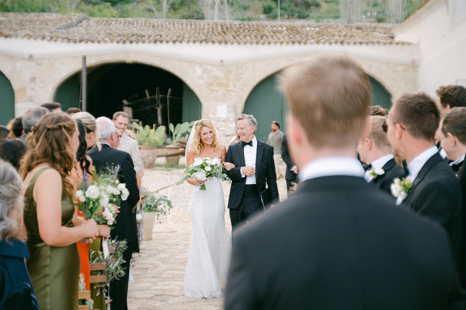 Close-up of Emma and Chris standing on the stone platform overlooking the ocean at their Tonnara di Scopello wedding ceremony.