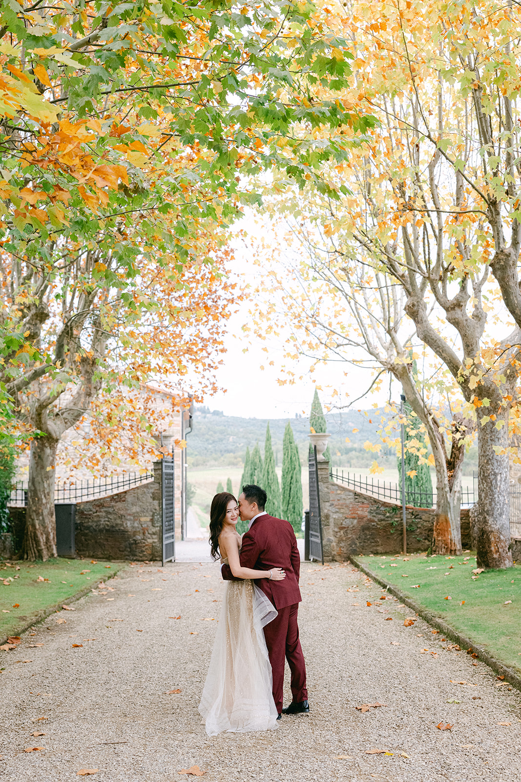 bride and groom walking through autumn gardens at Tuscany wedding venue