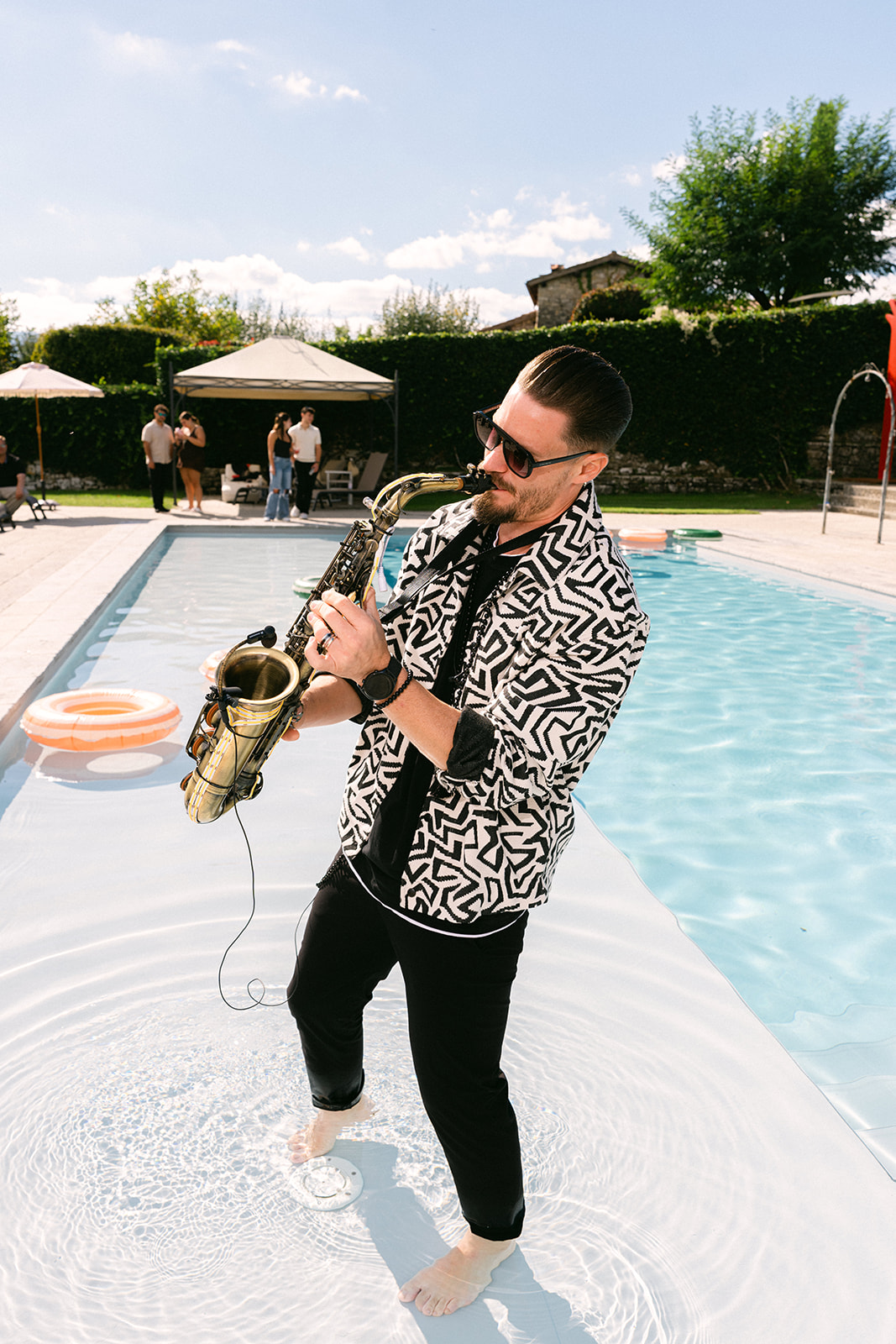 Guests enjoying live saxophone music during a Tuscany wedding pool party