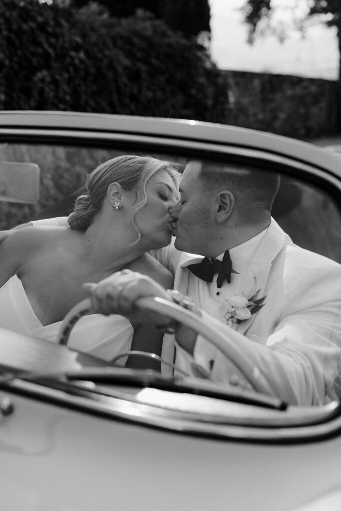 Luxury Tuscany wedding couple portraits in a vintage italian car with rolling hill views
