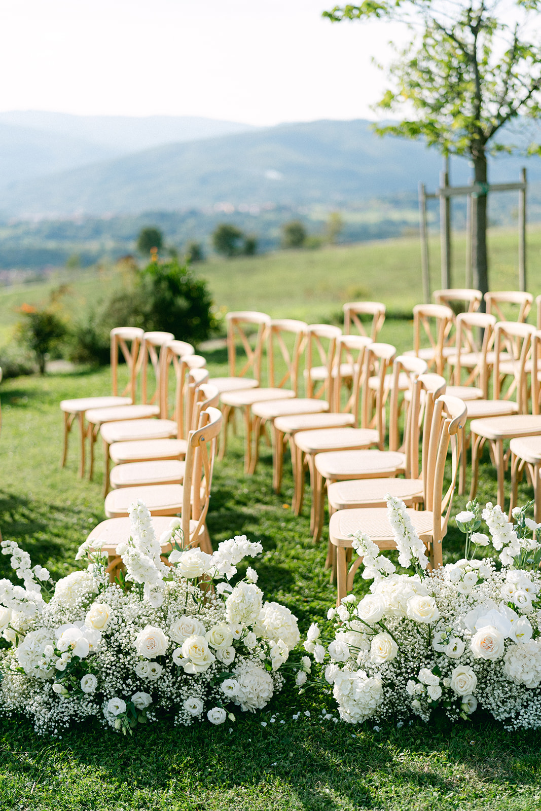 Romantic Tuscany wedding ceremony with white floral design and countryside views