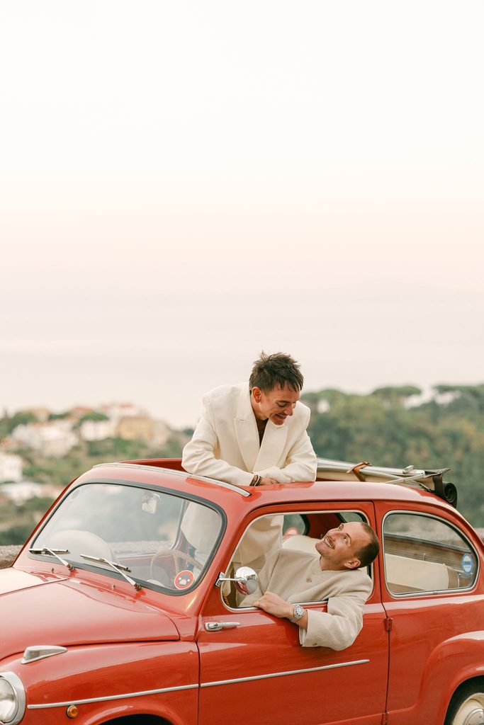 Andrea Gallucci - Destination Wedding Photographer- Amalfi Coast Positano Santorini Barcellona Rome Ravello Paris New York Gay couple posing beside a vintage red Fiat during their wedding welcome party in Italy